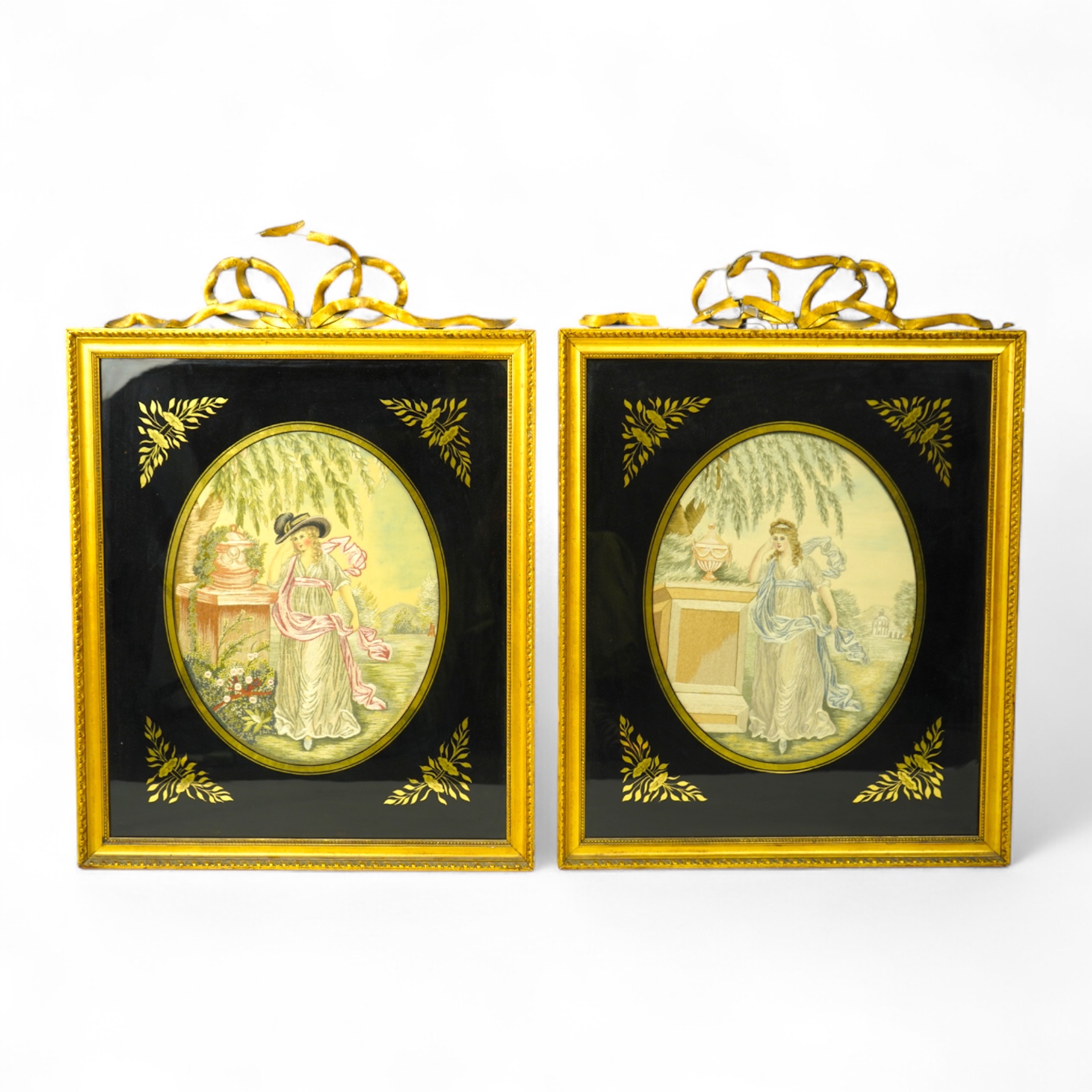 A pair of early 20th century oval silk embroideries of ladies standing by classical stone urns in a garden. Worked in pastel shades in silk using mostly stem stitch. Their faces, arms, hands and back ground silk hand pai
